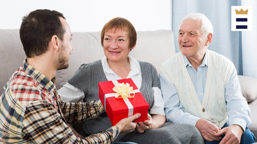 Child gives red gift to their smiling parents.