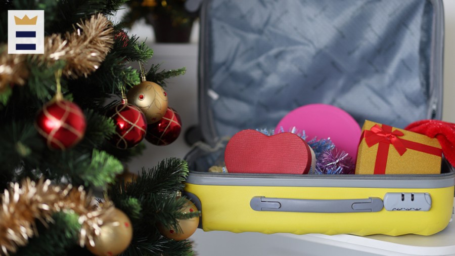 Yellow suitcase with gifts inside of it sits next to a holiday tree.