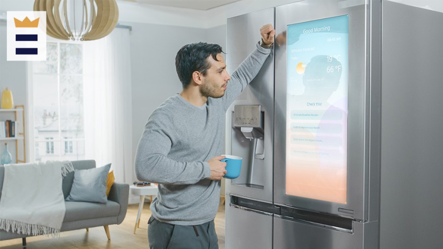 Person holding a mug leans against refrigerator.