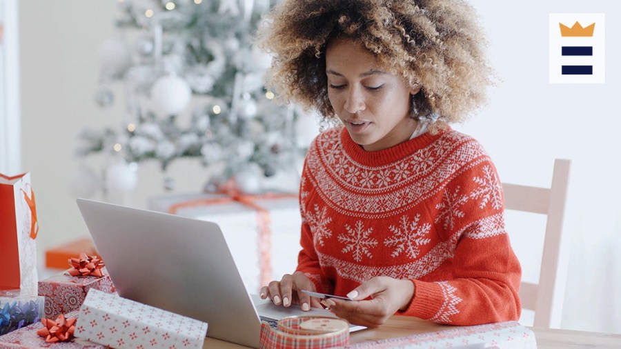 Woman in a red holiday sweater using a credit card and laptop to make an online purchase