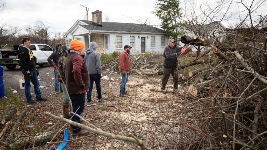 Randy Fathdruckner, right, cuts off tree branches from a fallen tree caused by a tornado in Bowling Green, Ky.