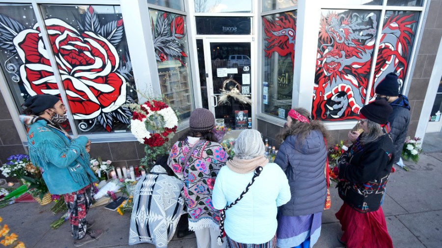 Mourners gather outside the door of a tattoo parlor on South Broadway in Denver, one of the scenes of a shooting spree that left six people dead