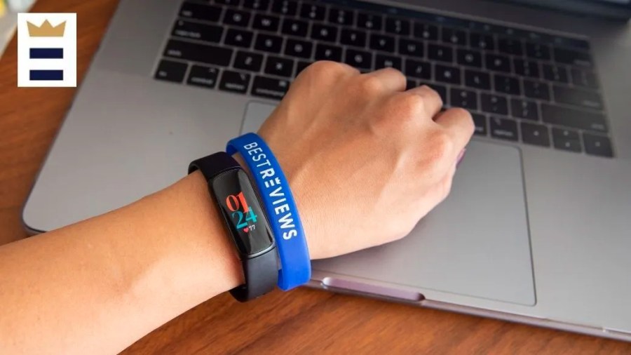 Person wearing a Fitbit and a BestReviews bracelet while working on a laptop