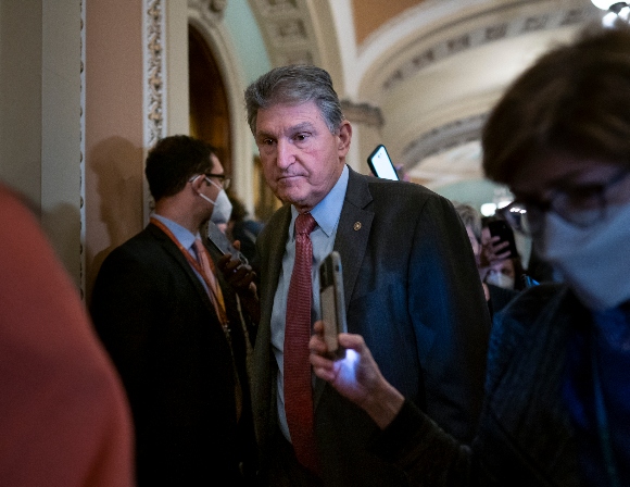 Sen. Joe Manchin, D-W.Va., makes his way through a crowd of reporters 