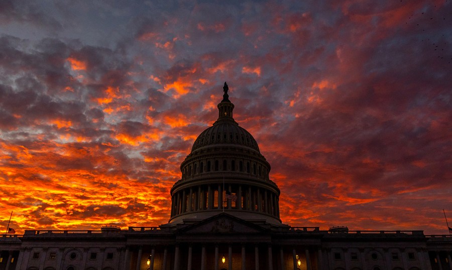 The sun sets behind the U.S. Capitol with orange, purple and blue hues