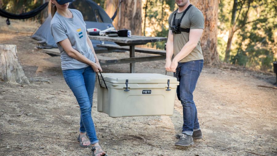 two people carrying a Yeti cooler