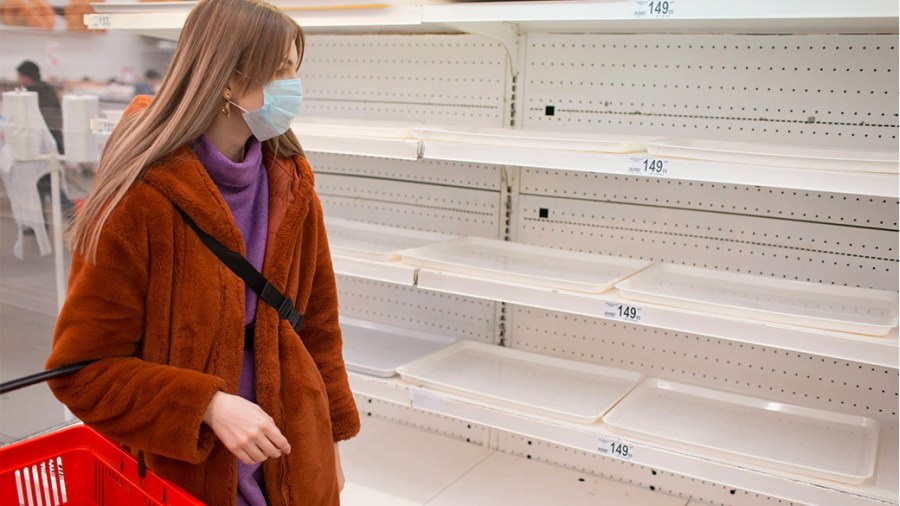 Woman in a grocery store looking at empty shelves