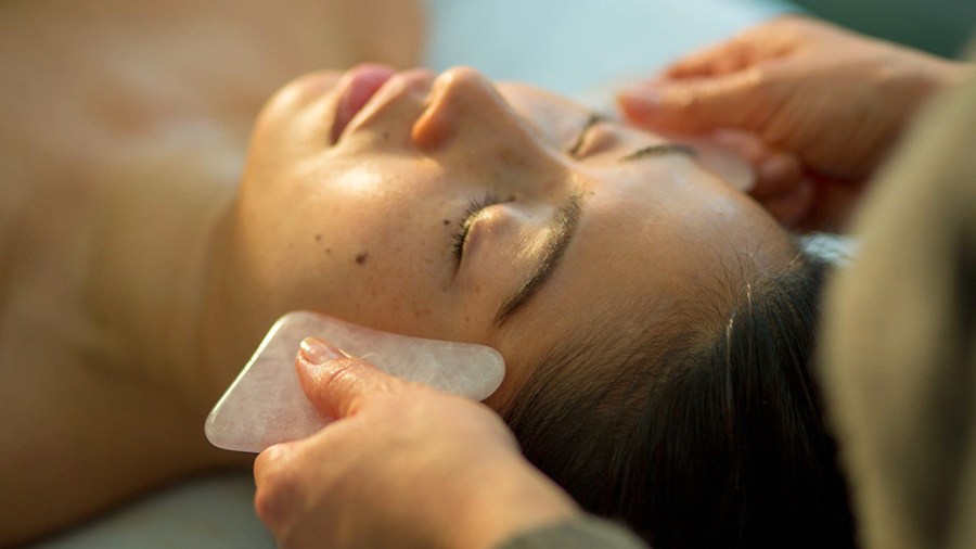 Person receiving a facial using gua sha facial tools