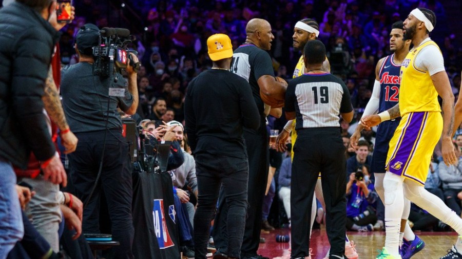 Lakers star Carmelo Anthony, top center, is held back by officials after having a word with a fan.