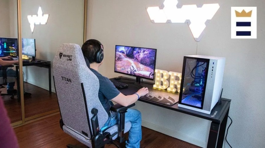 Person sitting at a desk playing video games on a desktop computer