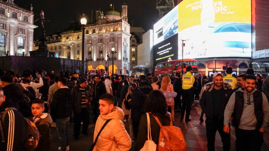 People, some wearing masks, in Piccadilly Circus, as they gather to celebrate New Year's Eve, in London