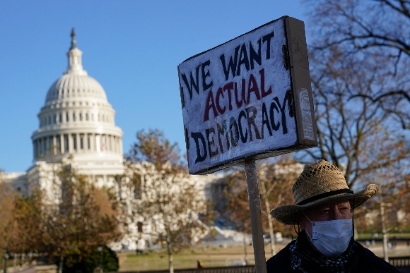 Protester David Barrows carries a sign during a rally to press Congress to pass voting rights protections and the "Build Back Better Act"