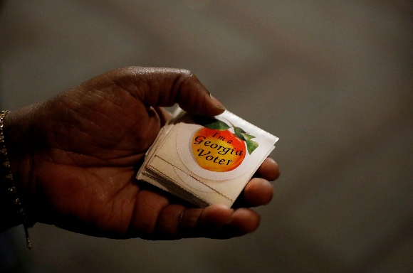 A poll worker hands out stickers to voters after they cast their ballots at a precinct on election day in Atlanta