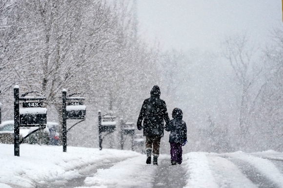 People go for a walk as snow falls Sunday, Jan. 16, 2022, in Nolensville, Tenn.