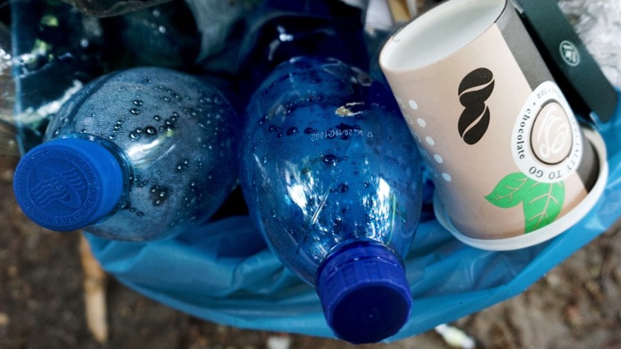 Plastic bottles and 'to go' coffee cup are pictured in a garbage can in a public park