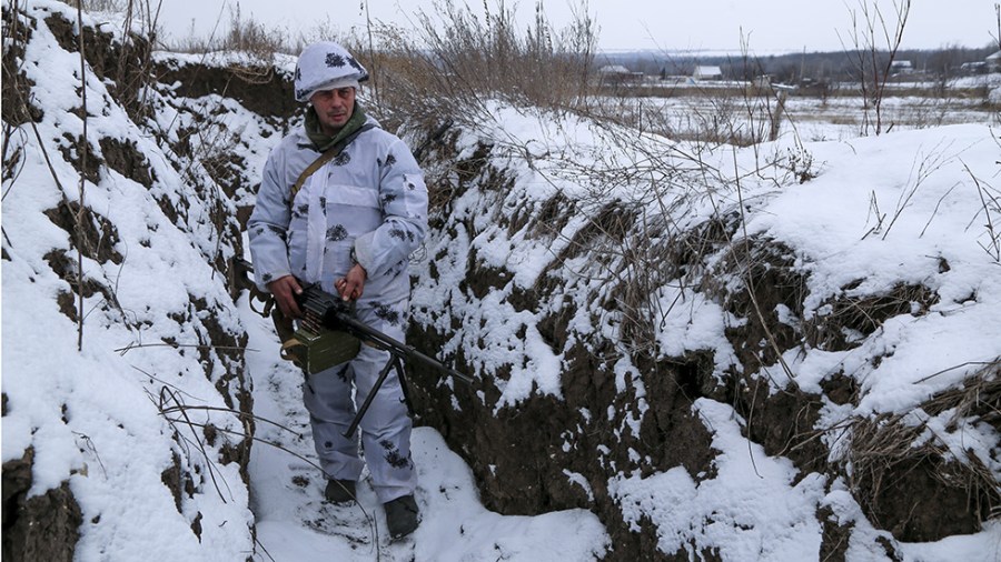 A serviceman holds his machine gun in a trench near eastern Ukraine.