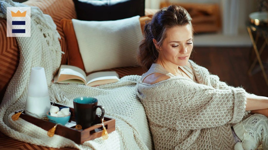 Woman wearing a cozy beige cardigan drinking tea and reading a book