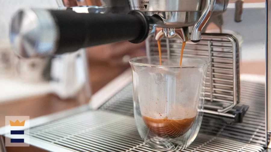 An espresso machine dripping liquid into a clear glass cup