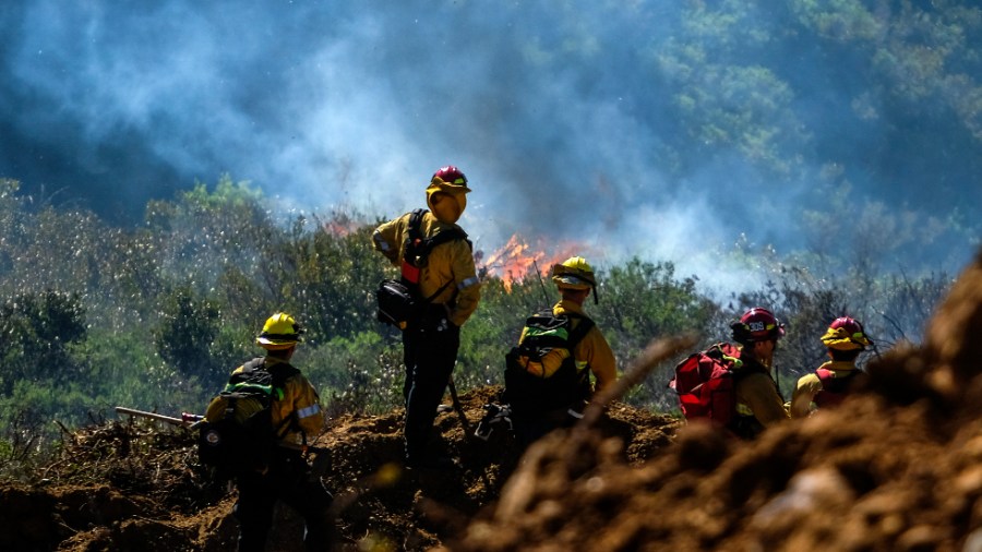 Firefighters watch as a wildfire burns outside Laguna Beach, Calif.