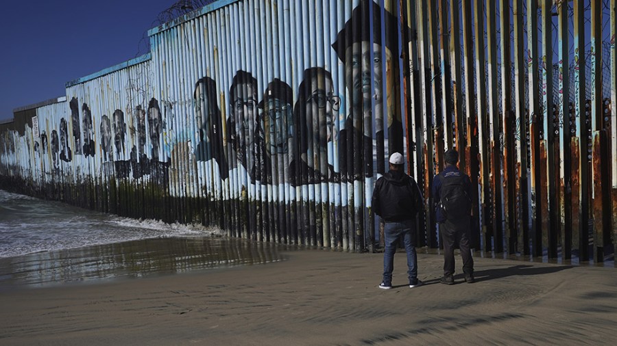 People walk near the border wall