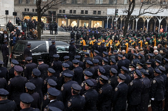 A hearse carrying the casket of NYPD officer Jason Rivera prepares to pull away after Rivera's funeral service