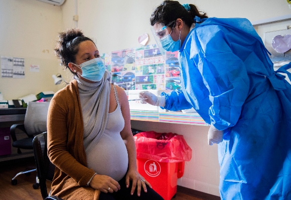 A nurse gives a shot of the Pfizer vaccine for COVID-19 to a pregnant woman