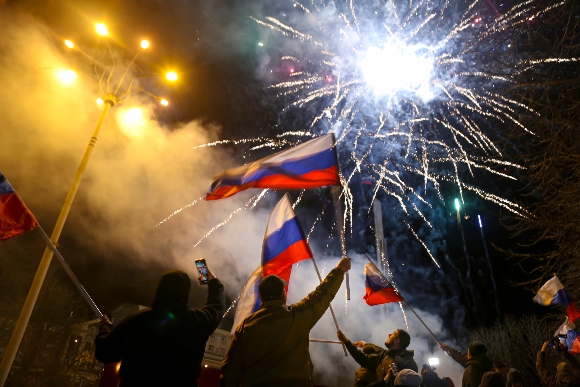 People wave Russian national flags celebrating the recognizing the independence in the center of Donetsk