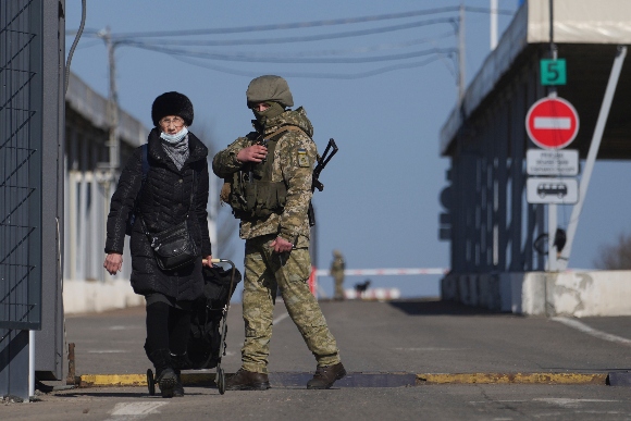 A woman crosses a checkpoint from the territory controlled by Russia-backed separatists to the territory controlled by Ukrainian forces in Novotroitske