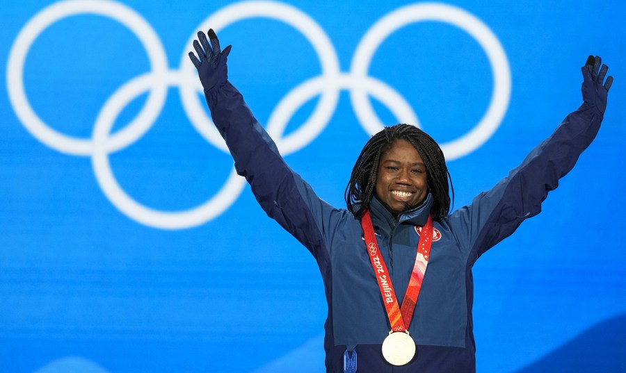 A gold medalist raises her arms during the medal ceremony