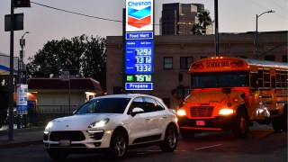 Gas prices on a blue board are seen at a Los Angeles gas station with cars passing by