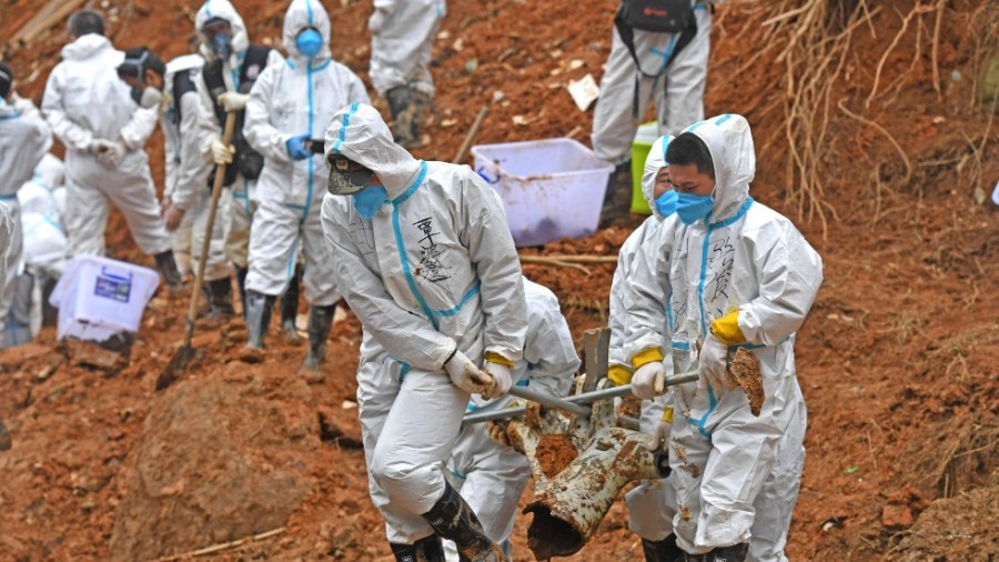 In this photo released by Xinhua News Agency, rescuers carry a piece of plane wreckage at the site of Monday's plane crash in Tengxian County