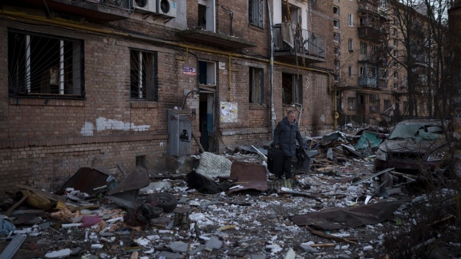 A resident carries a suitcase with his belongings after his building was heavily damaged by bombing in Kyiv, Ukraine