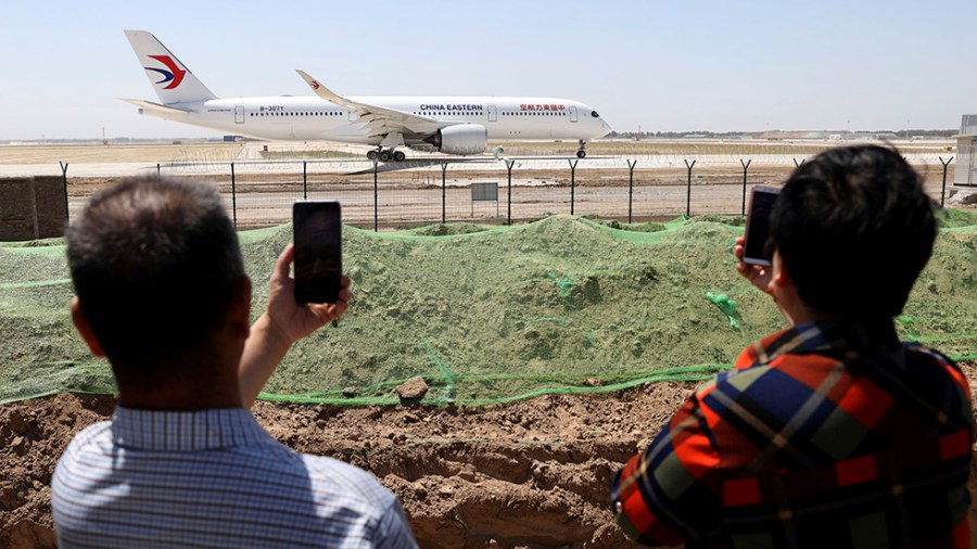 Residents watch as a China Eastern passenger jet prepares to take off