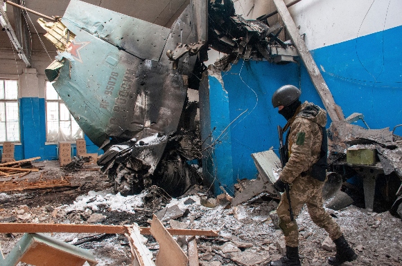 Ukrainian serviceman walks past the vertical tail fin of a Russian Su-34 bomber lying in a damaged building in Kharkiv