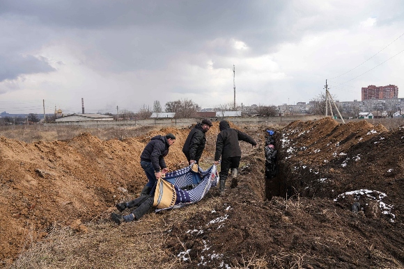 Dead bodies are put into a mass grave on the outskirts of Mariupol