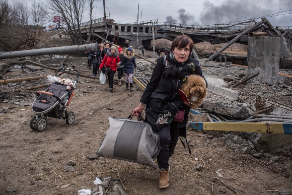 People cross an improvised path under a destroyed bridge while fleeing the town of Irpin, Ukraine