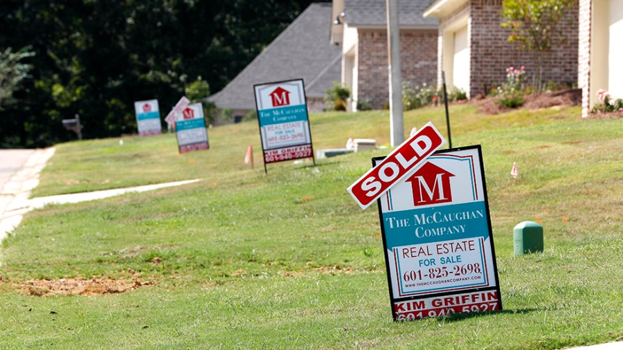 A "sold" sign sits atop a realty company's lawn sign