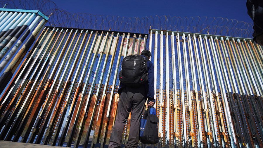 A migrant waits on the Mexican side of the border