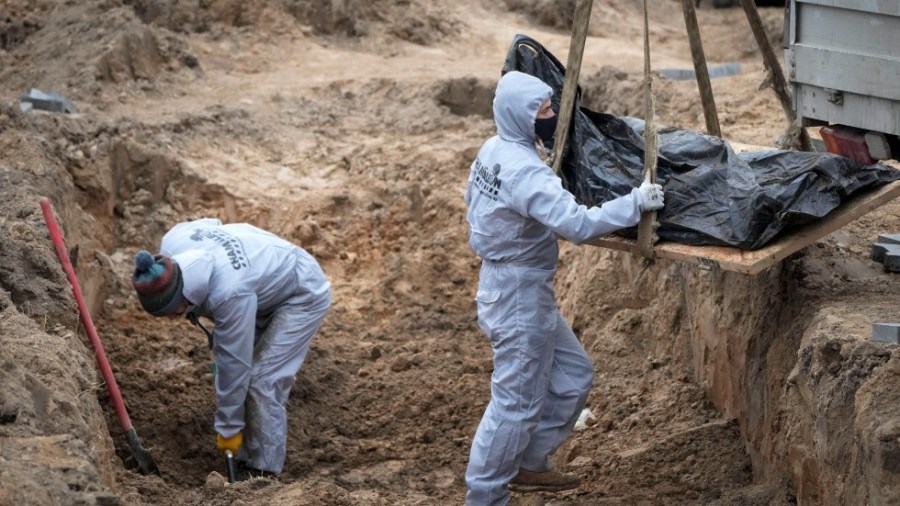 Men wearing protective gear exhume the bodies of civilians killed during the Russian occupation in Bucha