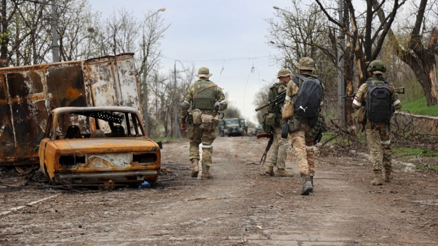 Servicemen of Donetsk People's Republic militia walk past damaged vehicles during a heavy fighting in an area controlled by Russian-backed separatist forces in Mariupol