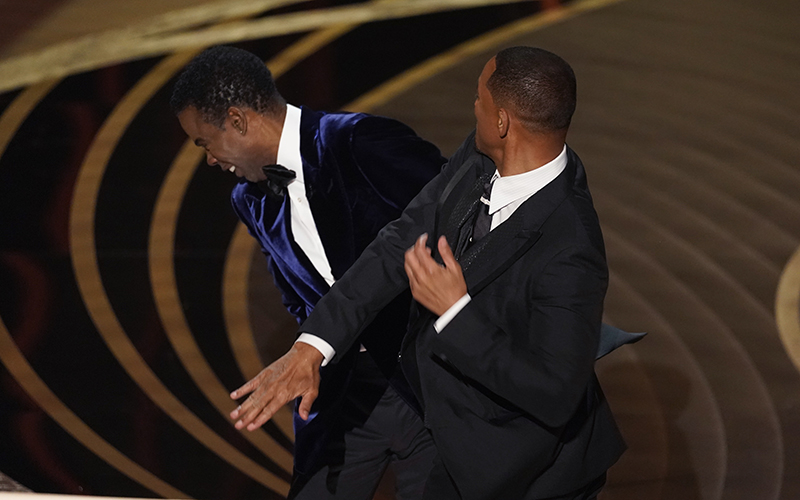 Will Smith, right, hits presenter Chris Rock on stage