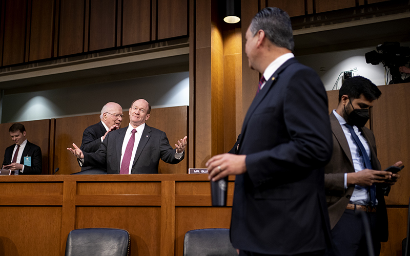 Sen. Chris Coons, left behind podium, gestures as speaks with Sen. Alex Padilla