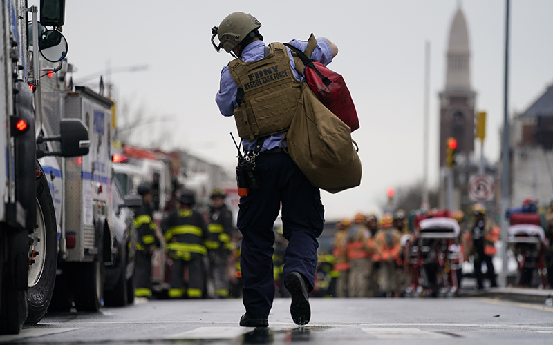 FDNY rescue task force worker is seen center walking toward other emergency personnel blurred in the background