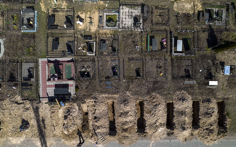 As seen from above in an aerial shot, a cemetery worker takes a rest from working on the graves of civilians killed in Bucha