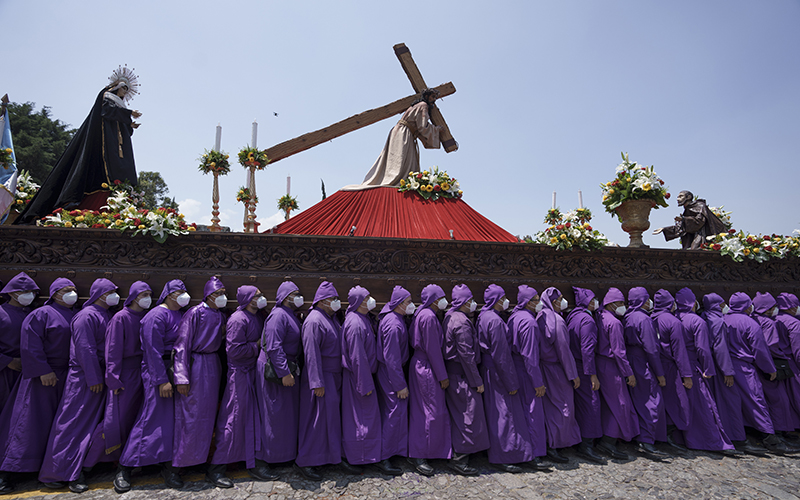 Cucuruchos dressed in royal purple carry a statue of Jesus Christ