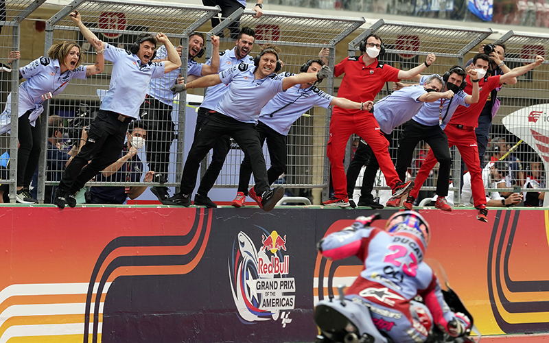 Members of the Gresini Racing team lean forward over the track as they celebrate