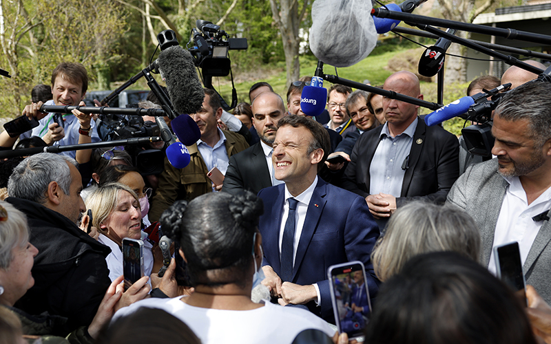 Emmanuel Macron surrounded by reporters, medical staff and supporters