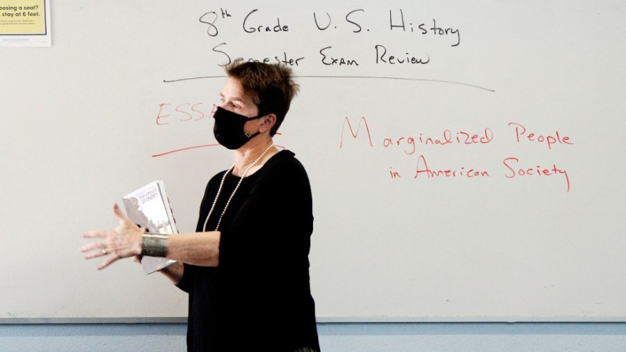 History teacher Wendy Leighton holds a copy of "They Called us Enemy," about the internment of Japanese Americans, while speaking about marginalized people with her students