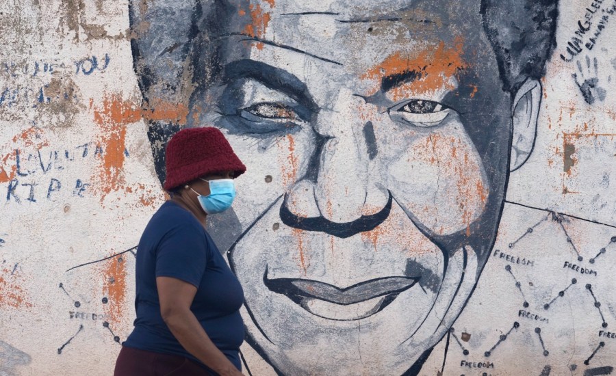 woman wearing mask walking past mural