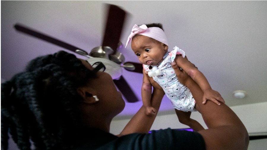 A mother lifts her daughter into the air.